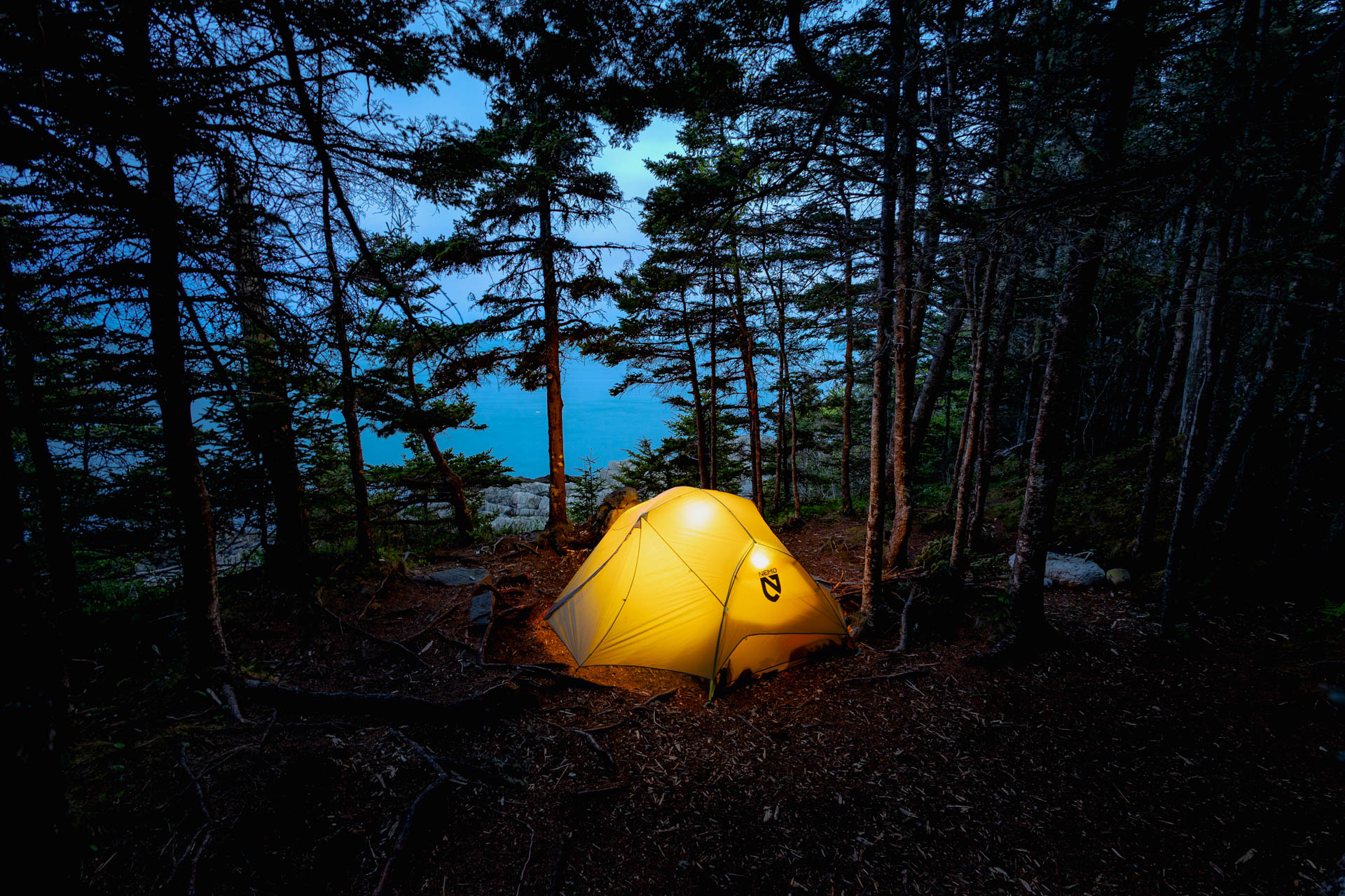Illuminated tent above the coast at dusk